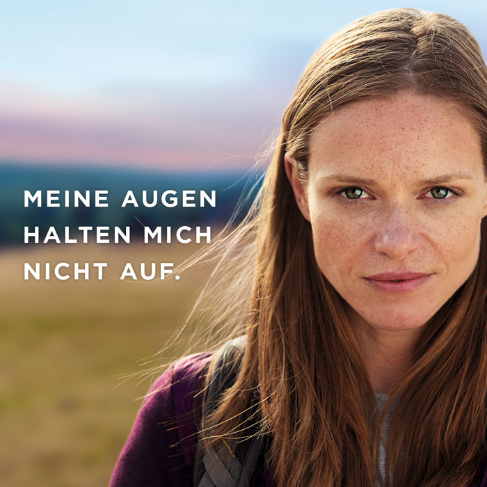 Junge Frau guckt beim Wandern gradeaus in die Kamera.